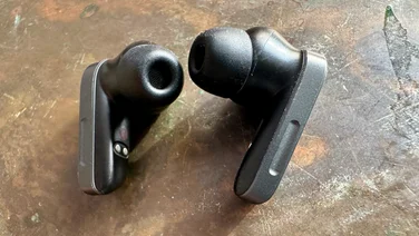 A close up of the Edifier NeoBuds Planar earbuds, pictured on a rustic surface