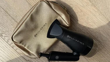 Bellissima Italia B-Travel gold travel bag with folded hair dryer resting on it