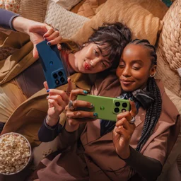 Two people lying next to each other, holding up their Motorola Edge 60 phones
