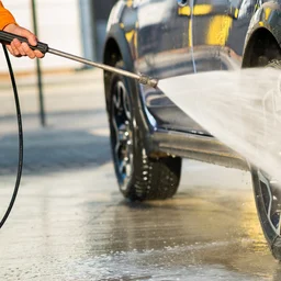 Close-up of person pressure washing SUV wheels